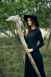 Side view of young woman standing in forest