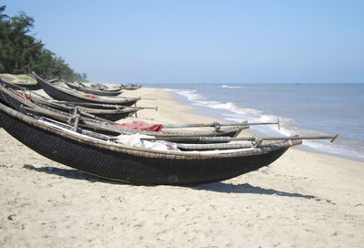 Boats moored at sandy beach on sunny day