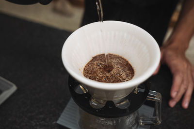 Cropped image of hand pouring coffee in cup