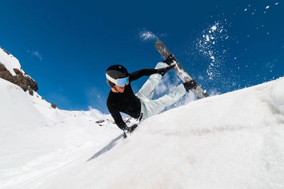 Young professional snowboarder rides in a large mountain snow park, sliding and splashing snow on a