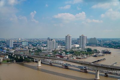 City at waterfront against cloudy sky