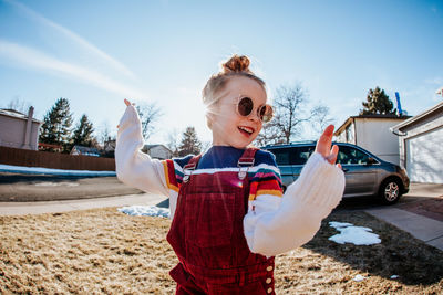 Close up of young girl dancing in front yard with sunglasses on