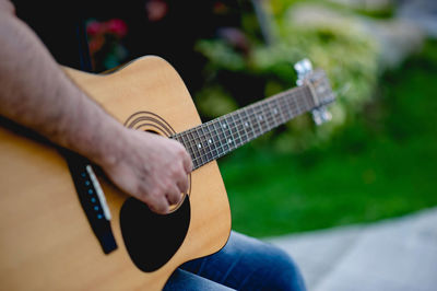 Midsection of man playing guitar outdoors