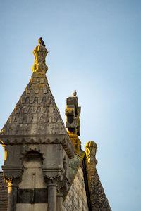 Low angle view of statue against building against clear sky