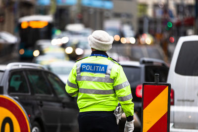 Rear view of man standing by street in city