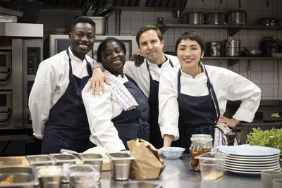 Portrait of smiling multiracial chefs standing in kitchen counter at restaurant