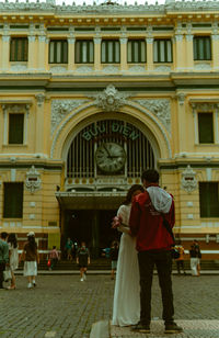 Rear view of woman standing in front of historic building
