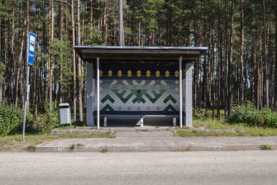 Traditional latvian symbols on the bus stop on road by trees in forest