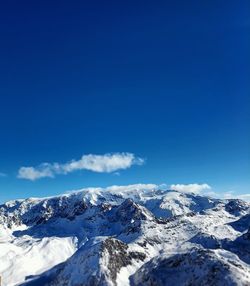 Low angle view of snow covered landscape against blue sky