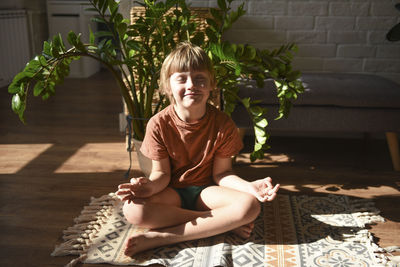 Boy with eyes closed meditating at home