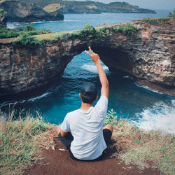 Rear view of man sitting on rock formation
