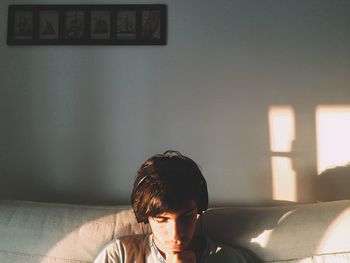 Young man listening music while sitting on sofa at home