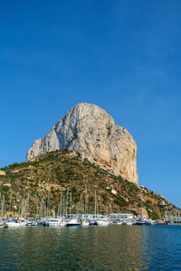 Sailboat on rock by sea against clear blue sky