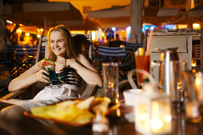 Young woman with cocktail sitting at restaurant