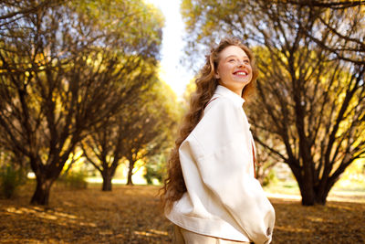 Portrait of young woman standing against trees
