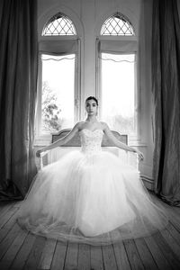 Portrait of young woman in dress sitting on bench at home