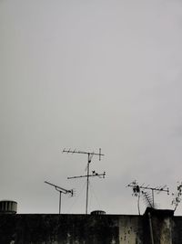 Low angle view of telephone pole on roof against sky