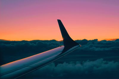 Close-up of airplane wing against sky during sunset