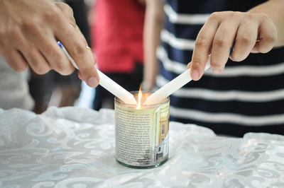 Close-up of people burning candles on table