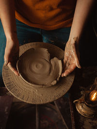 Woman makes plate of clay in pottery workshop, beautiful background, authentic atmosphere,