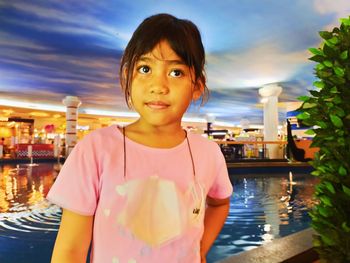 Portrait of smiling girl standing at illuminated park