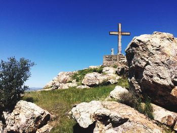 Low angle view of cross on rock formation at penon de penarroya pueblonuevo