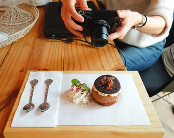 Midsection of woman photographing food on table