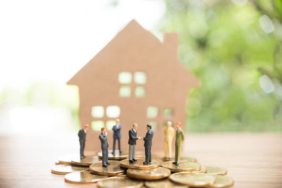 Close-up of figurines on coins by model house over table