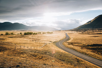 Scenic view of road by mountains against sky