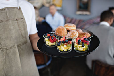 Midsection of owner holding food in serving tray at restaurant