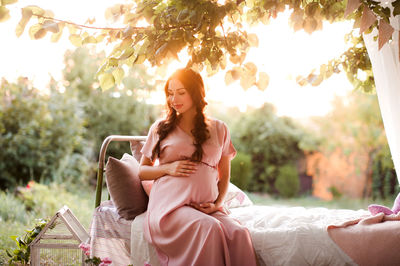 Expecting woman sitting on bed at park