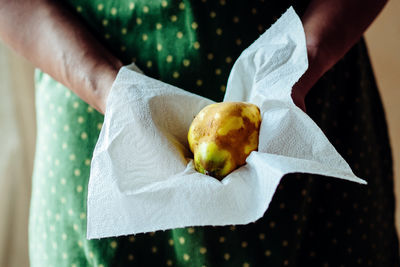 Midsection of woman holding coconut in napkin