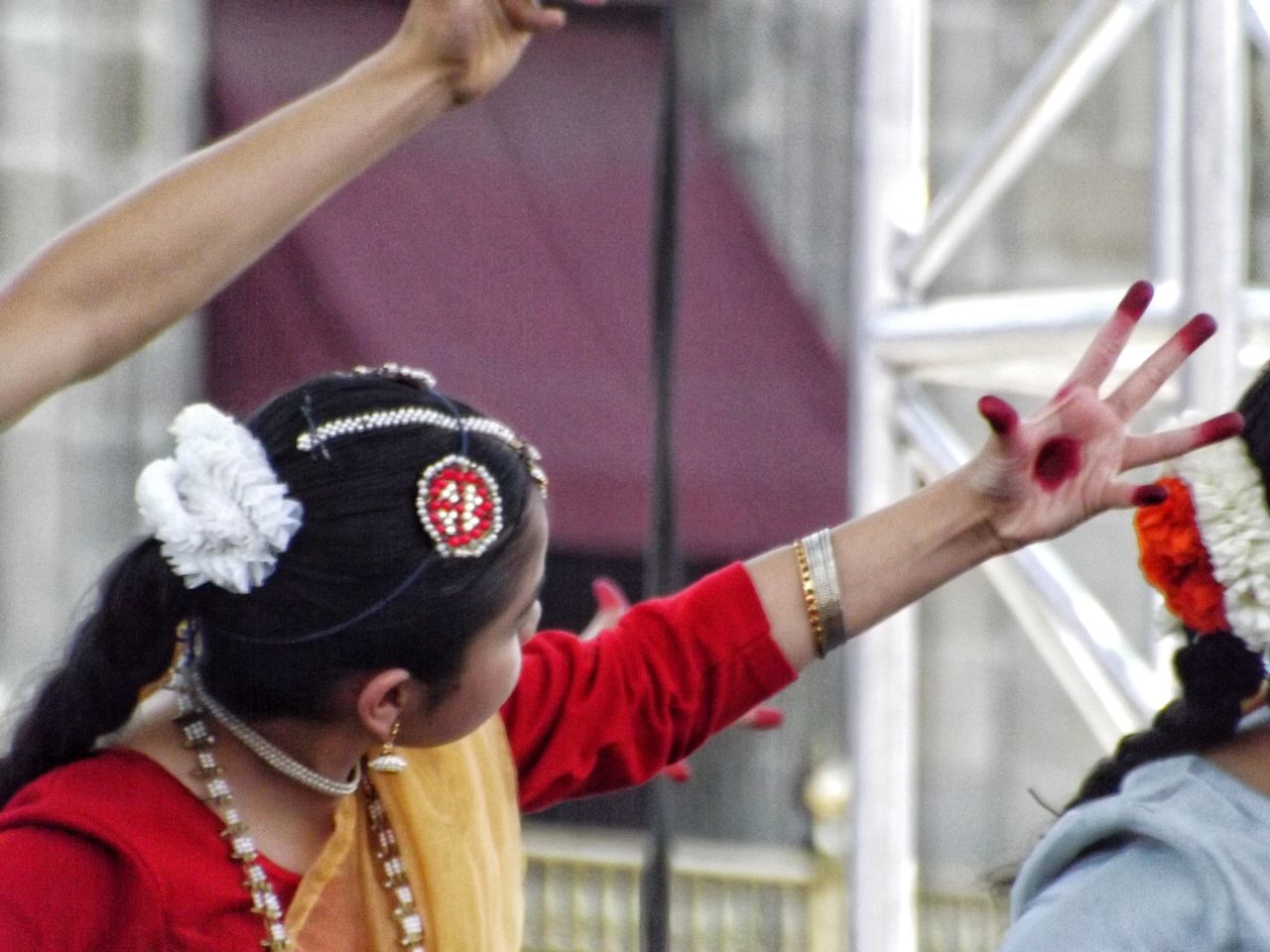 real people, women, headshot, focus on foreground, lifestyles, clothing, people, adult, portrait, leisure activity, traditional clothing, hand, red, men, human body part, architecture, holding, outdoors, hairstyle, human arm, human limb, arms raised