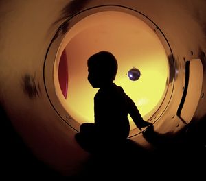 Silhouette boy in illuminated tunnel