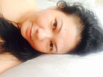 Portrait of young woman lying down on bed
