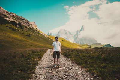 Rear view of man standing on mountain against sky