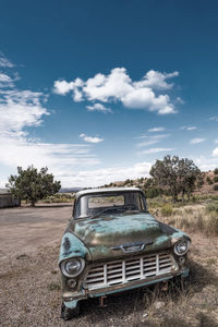 Abandoned car on field against sky