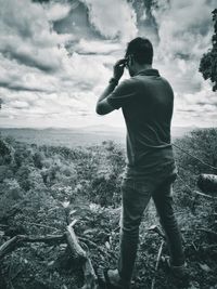 Rear view of man standing on field against sky