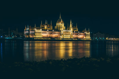 Illuminated church in front of river at night