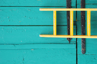 Tilt image of yellow ladder leaning on wooden wall