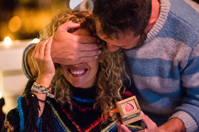 Man closing woman eyes with present holding in hand