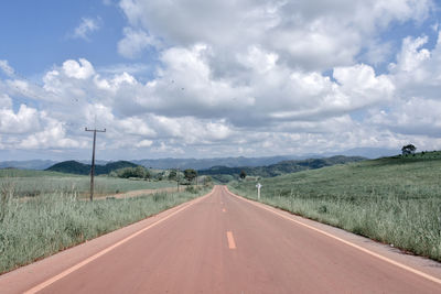 Empty road amidst landscape against sky