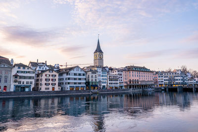 Buildings at waterfront against cloudy sky