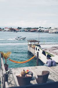 Man sitting on boat moored at sea against sky