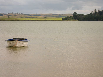 Boat moored in lake against sky