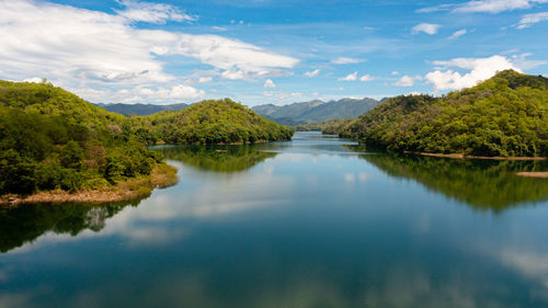 A river among mountains and hills with a reflecting blue sky and clouds. randenigala reservoir