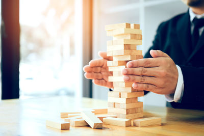 Midsection of businessman stacking wooden blocks on table in office