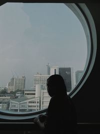 Rear view of man looking at cityscape against sky