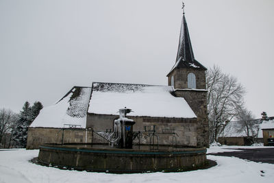 Built structure by snow covered building against sky