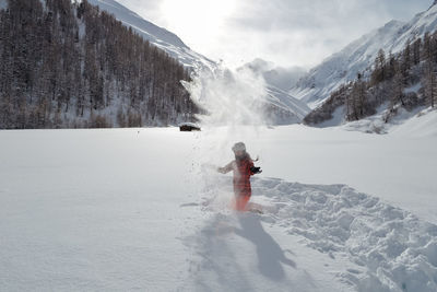 Woman standing on snow covered mountain against sky